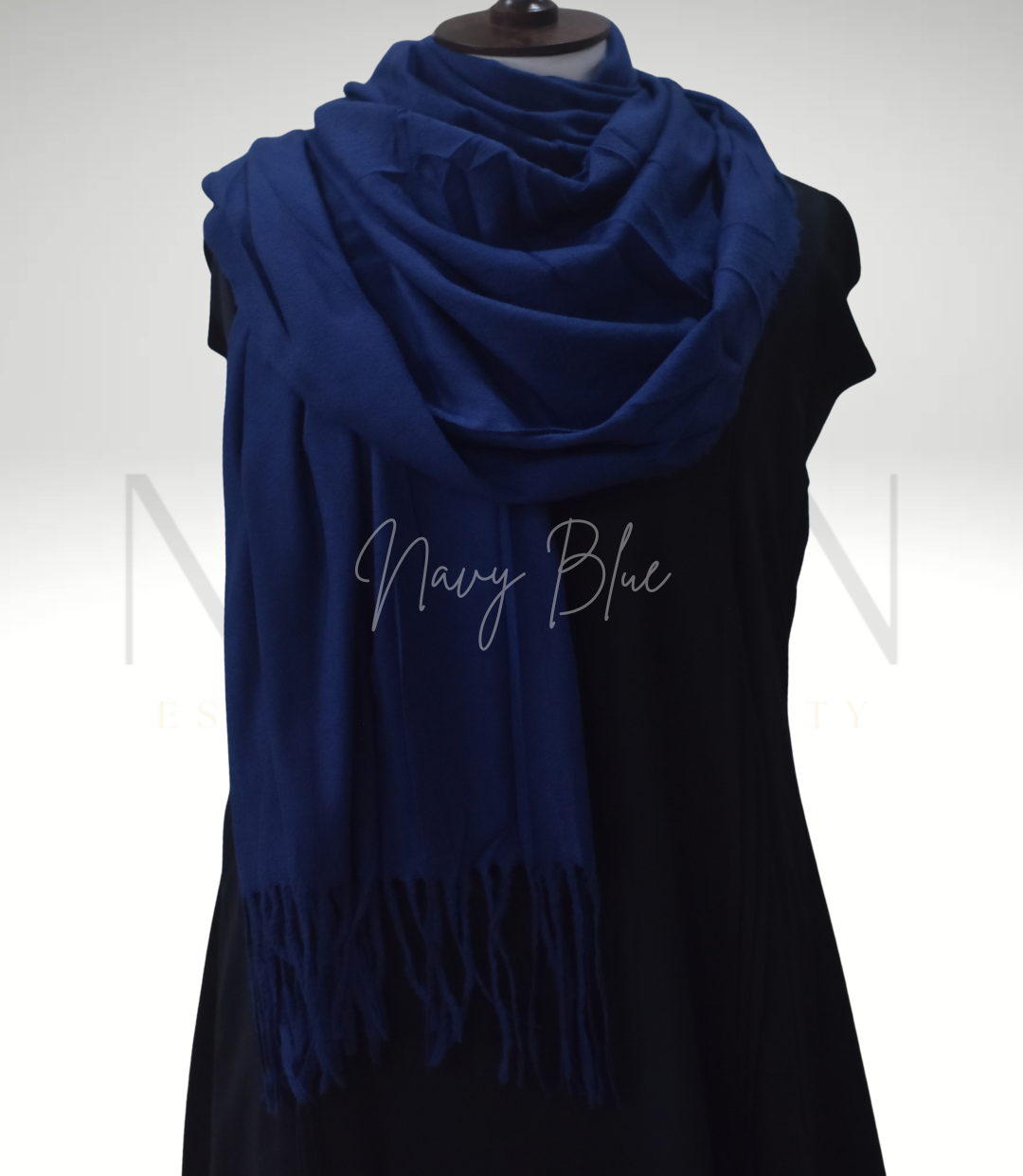 Navy blue scarf with fringe on a black dress against a white background